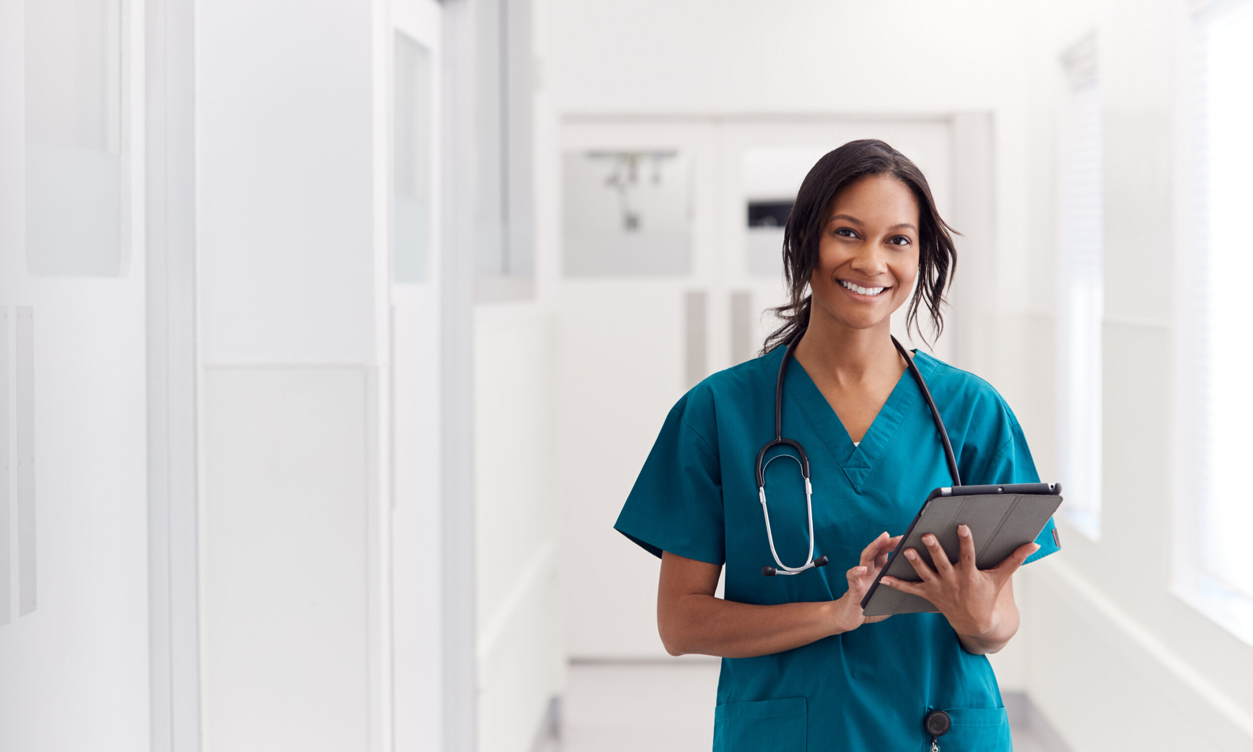 Healthcare professional holding a tablet in a clinic hallway, representing updated 2026 healthcare policies and resources affecting low-income families.