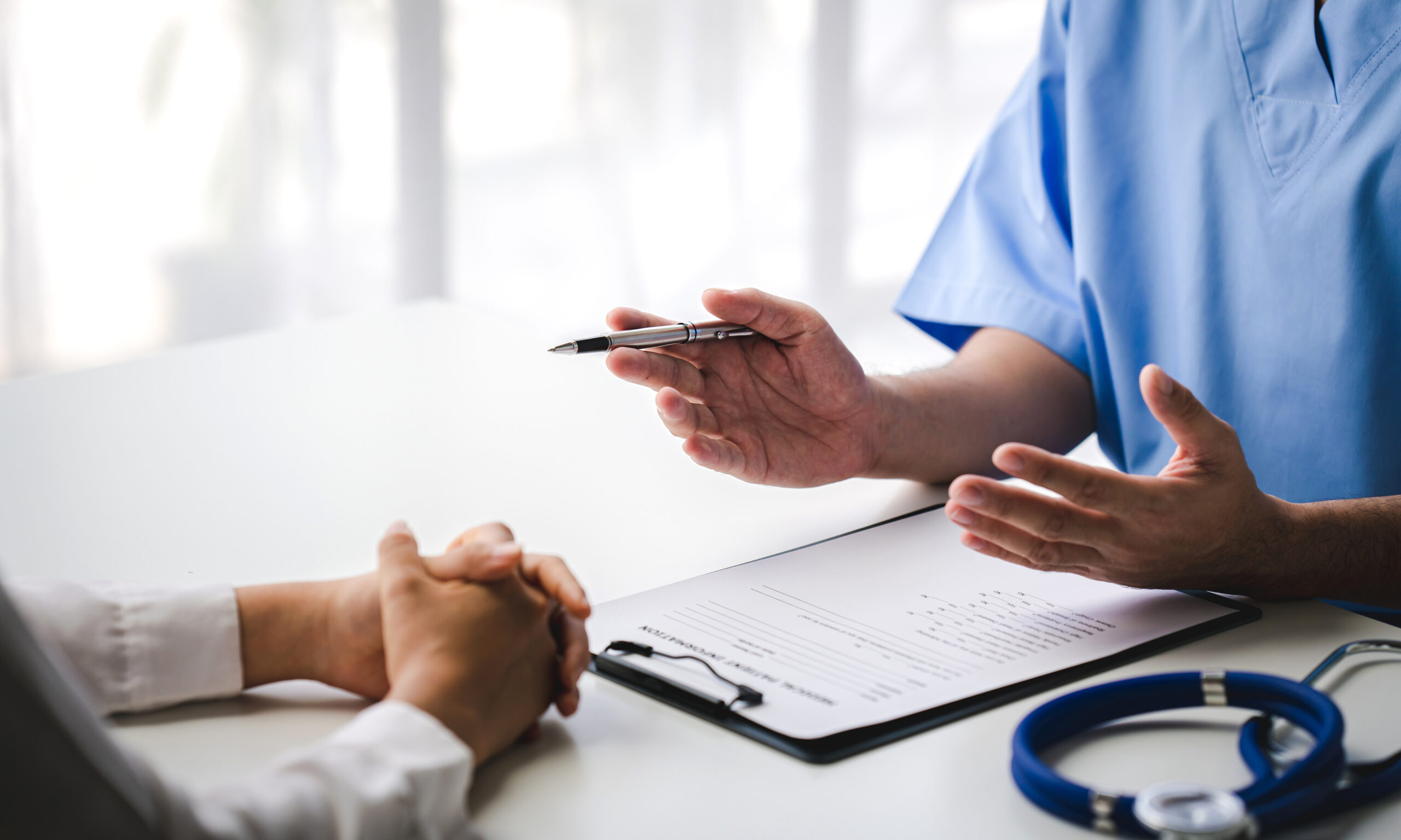 Doctor consulting with patient over paperwork showing how to apply for Medi-Cal in San Bernardino County
