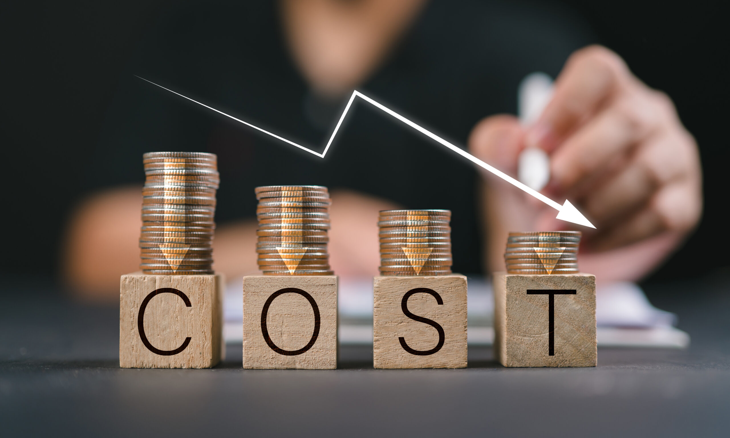 Coins stacked above wooden blocks spelling cost with a downward arrow representing reduced healthcare costs and sliding fee scale discounts.
