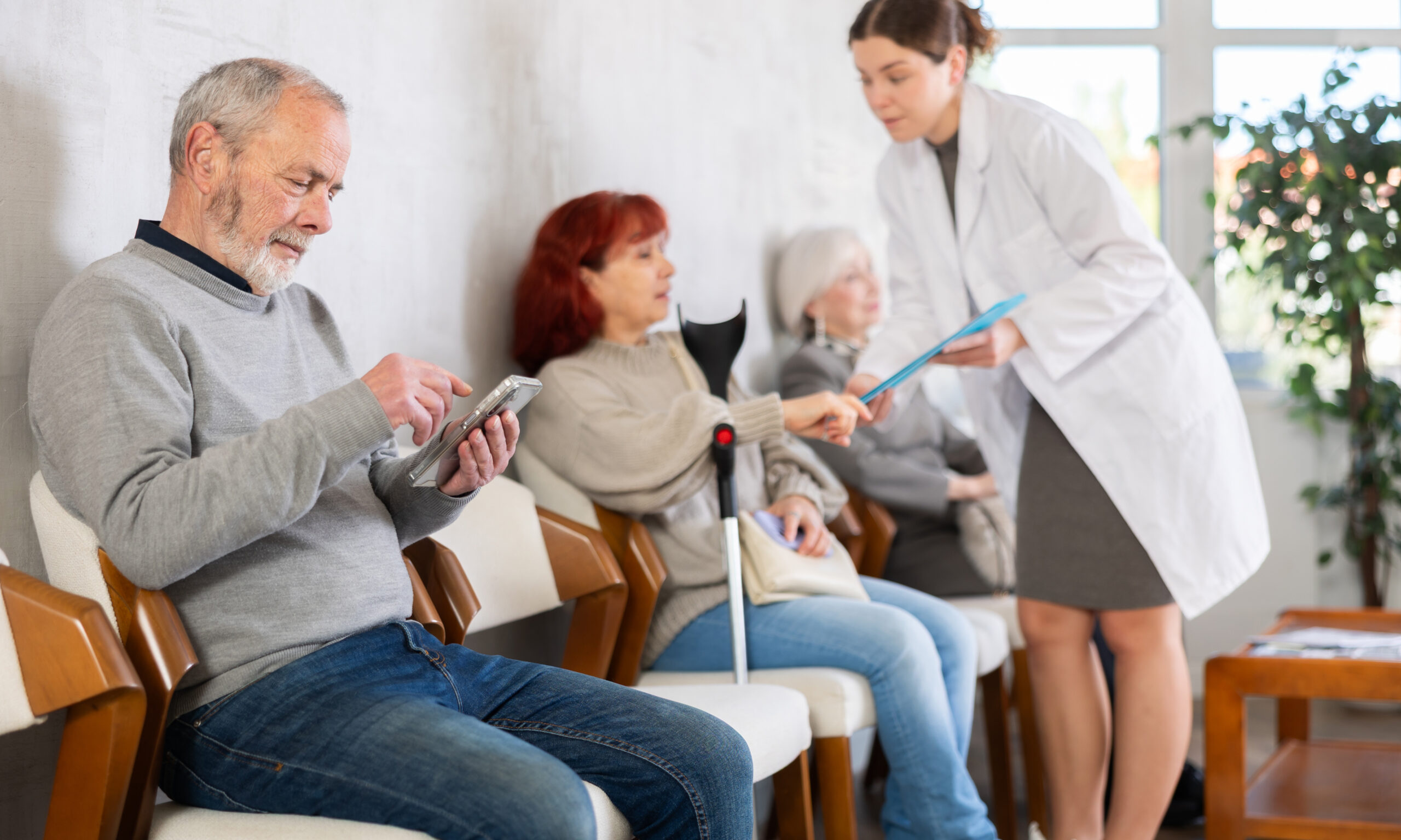 Patients waiting in clinic lobby while healthcare worker assists with paperwork for first doctor visit at community health center