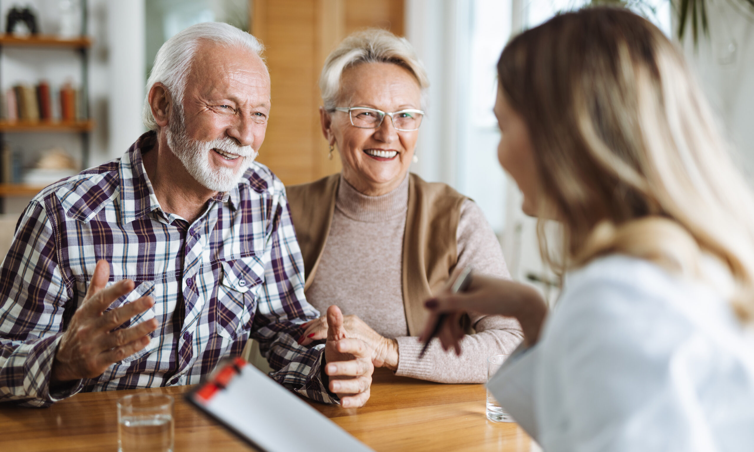 Older couple meeting with a healthcare representative reviewing information on a tablet, representing comparison of Medicare and Medi-Cal coverage options.