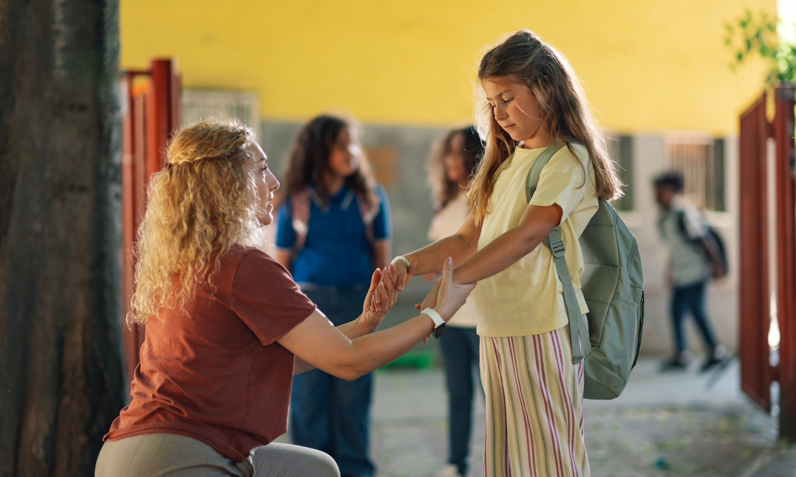 Parent reassuring a child outside school while discussing how to help kids manage back-to-school anxiety.