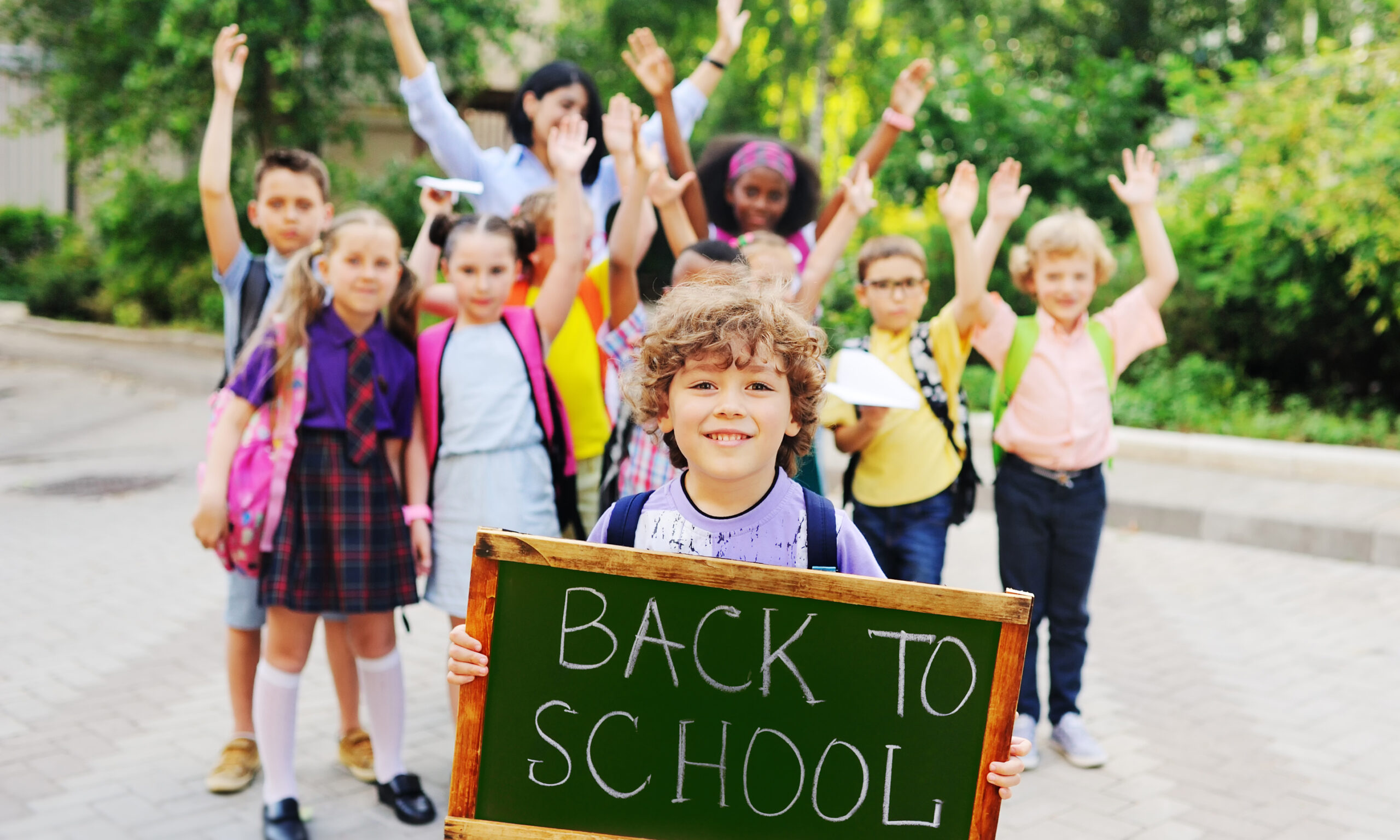 Students celebrating the first day of school while families prepare back-to-school health checklists, physicals, and vaccines.