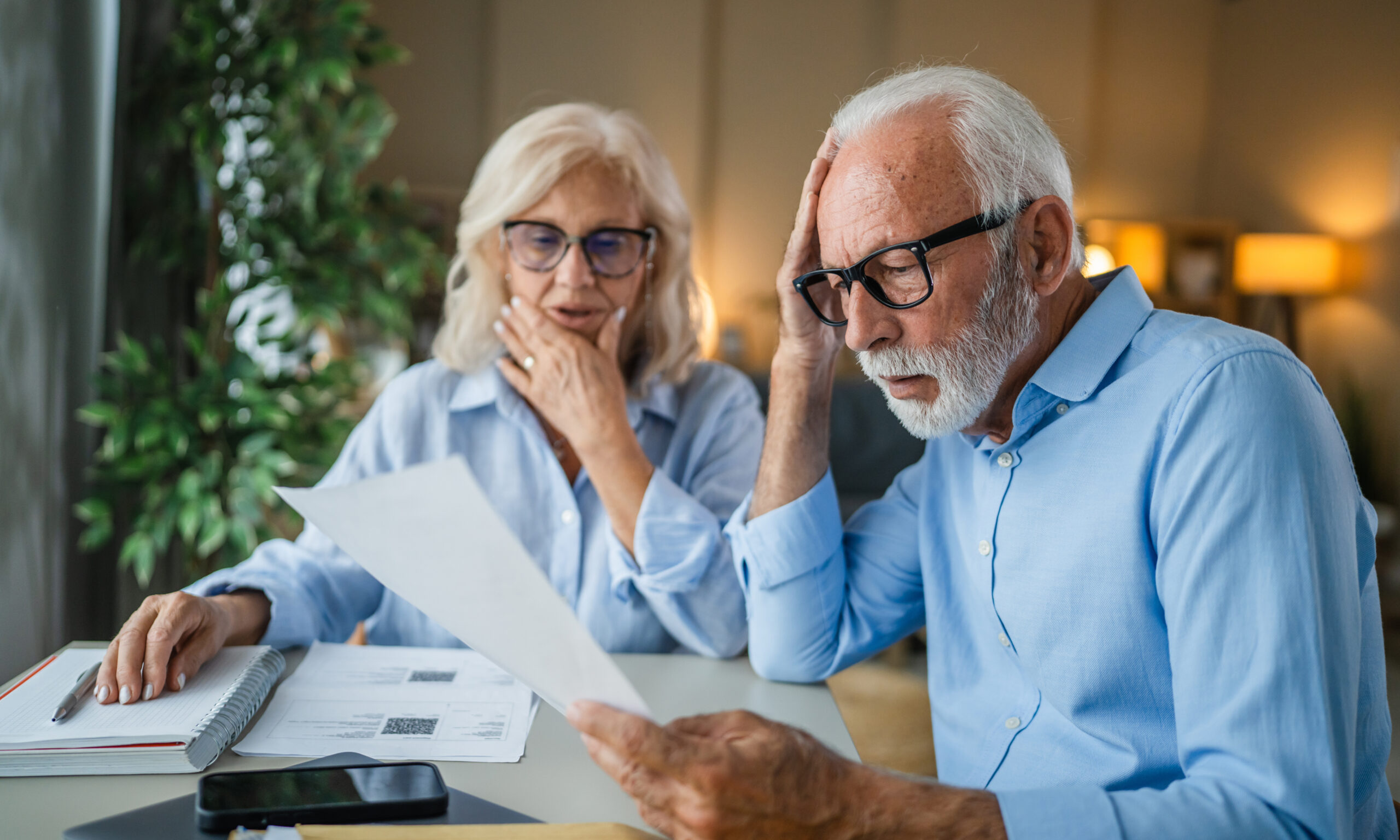Older couple reviewing paperwork together at a table with concerned expressions, representing questions about Medi-Cal income limits and eligibility guidelines for 2026.