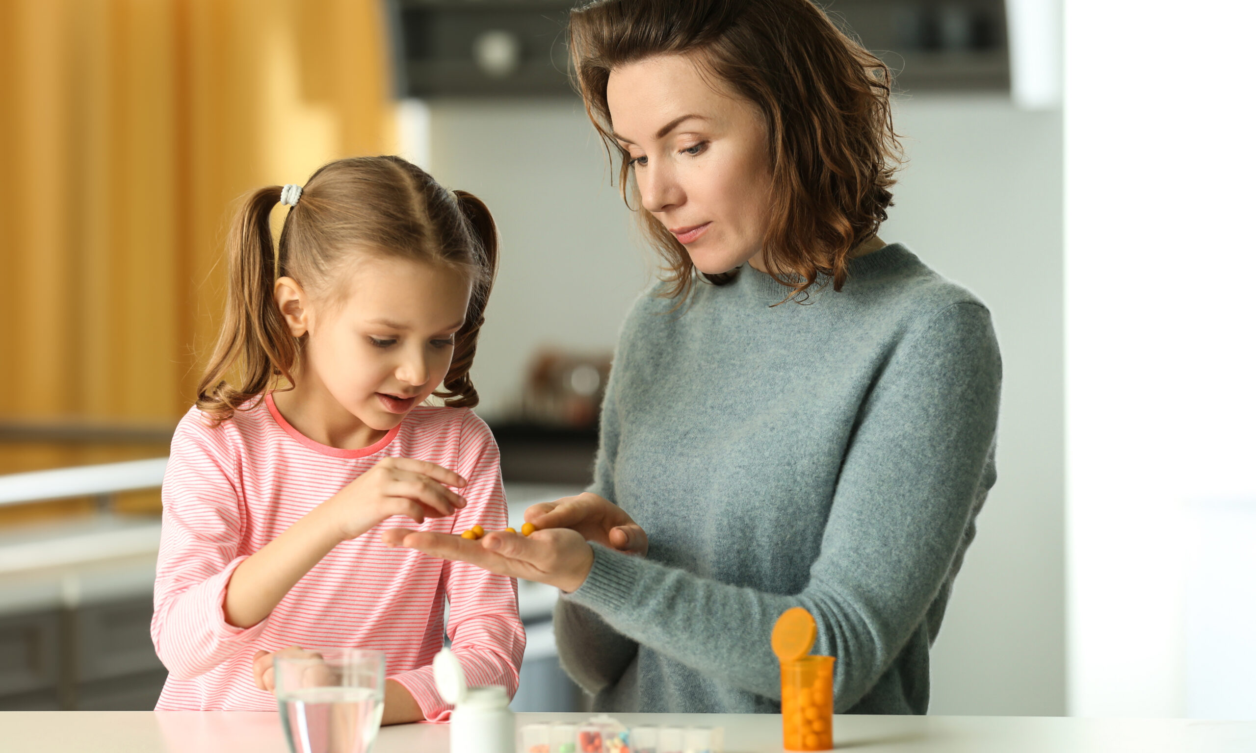 Parent helping a child take medication at home, representing safe medication management for school-age children and family health routines.